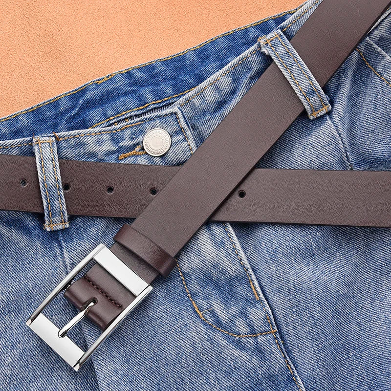 A brown PU leather belt with a silver metal pin buckle is shown across a blue denim shirt.