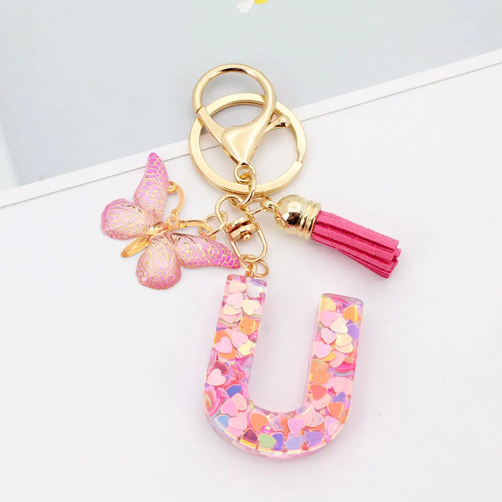 Alphabet letter acrylic keychain shaped like a pink butterfly with a gold ring and pink tassel