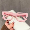 A hand holds a pair of pink square anti-blue light computer glasses against a white background.