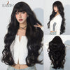 A woman modeling a long black wavy wig with bangs and a white top