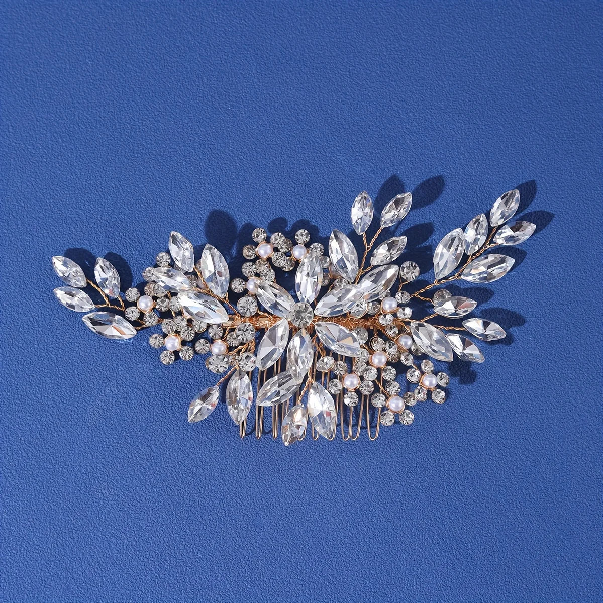 A delicate crystal and pearl hair comb and headband accessory displayed against a blue background.