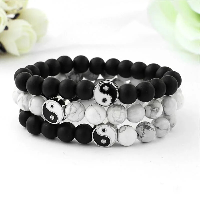 A stack of black and white Yin Yang hand string bracelets on a white background.