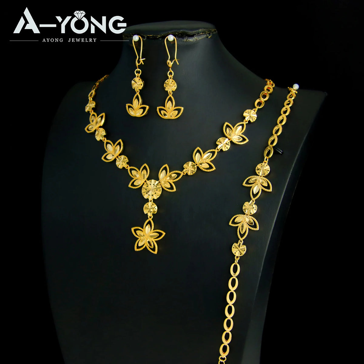 A set of luxury gold plated bridal jewelry featuring earrings and a necklace displayed on a black mannequin.