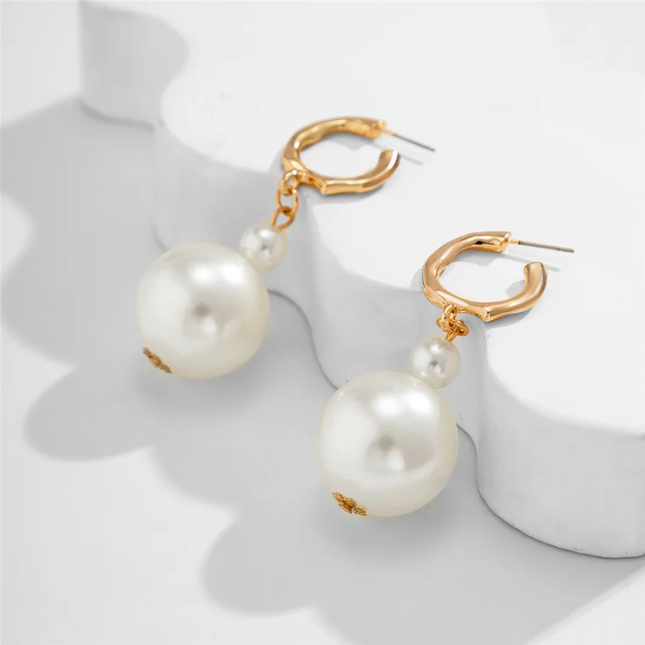 Collier de perles imitation or, avec pendentif rond, sur fond blanc.