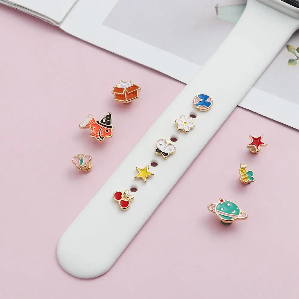 Una correa de reloj blanca presenta varios adornos metálicos decorativos en la banda de reloj de varios colores y formas.