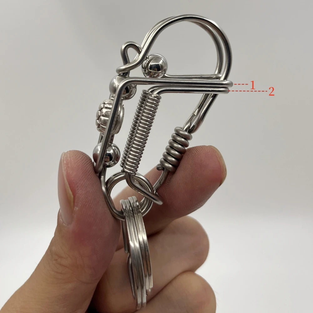 Une main tient un porte-clés mécanique en acier inoxydable avec ressort et anneau.