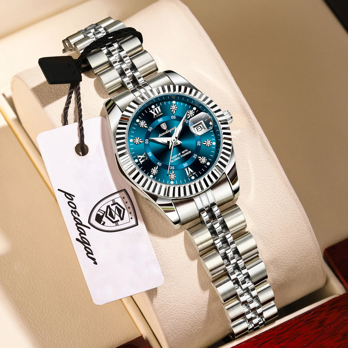 A silver wristwatch with a blue face and black bezel is displayed on a light-colored box.