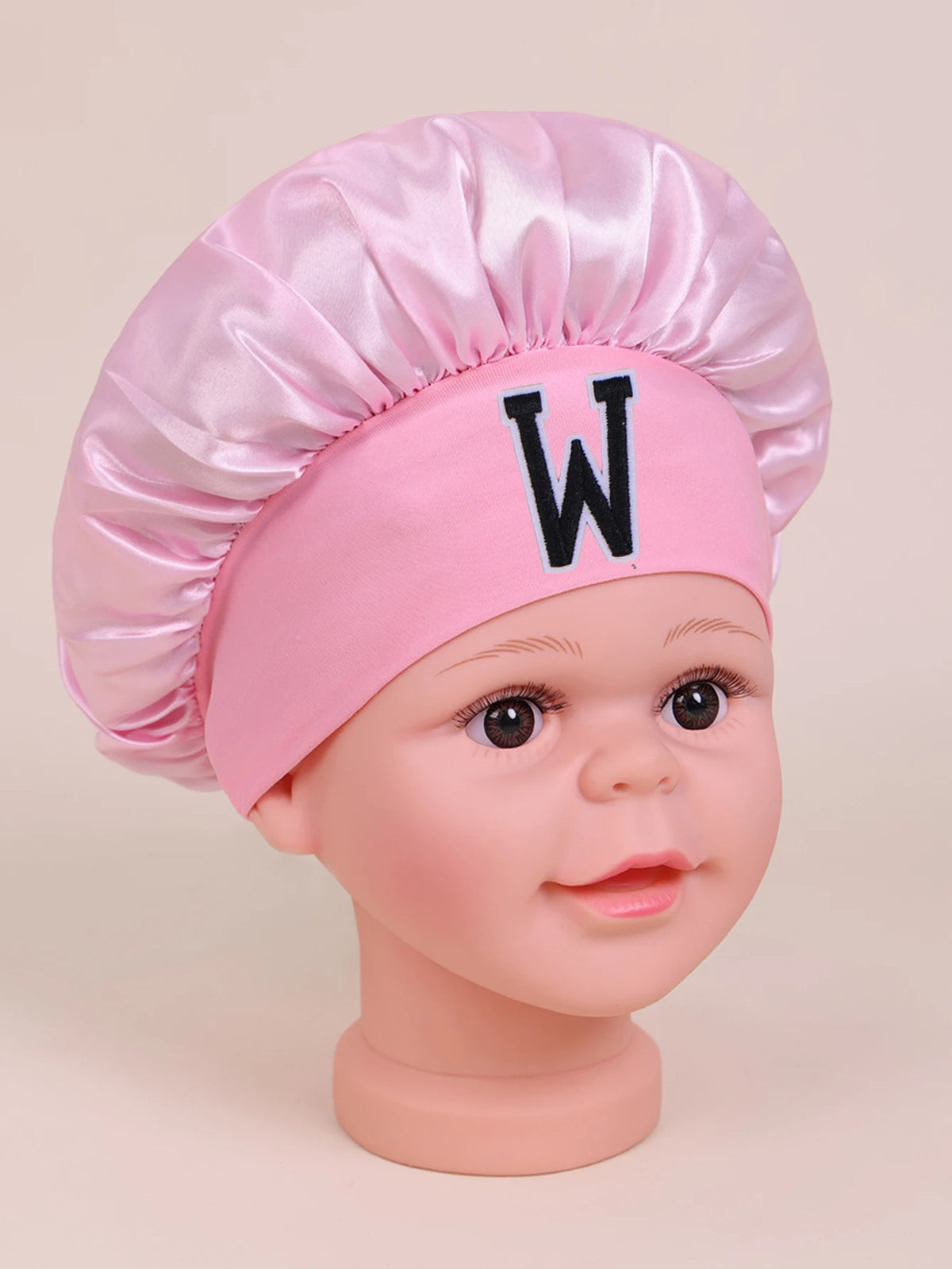 Pink sleep cap for kids with a white letter W embroidered on the front