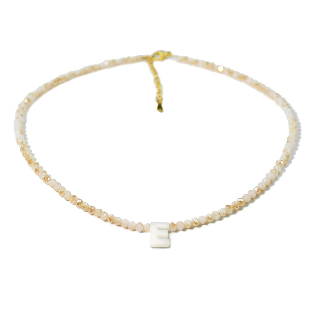 A delicate necklace made of mother of pearl beads with crystal accents and a small initial charm.