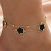 Gold five-leaf clover anklet worn on a person's ankle.