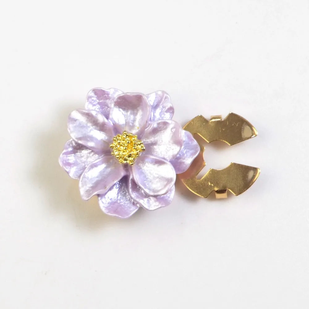A light purple pearlescent flower button cover with a gold butterfly shape.