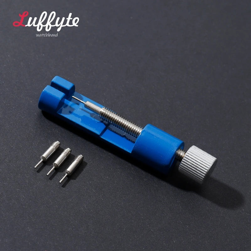 A blue watchband repair tool kit showing a metal tool and several small pins on a dark surface.
