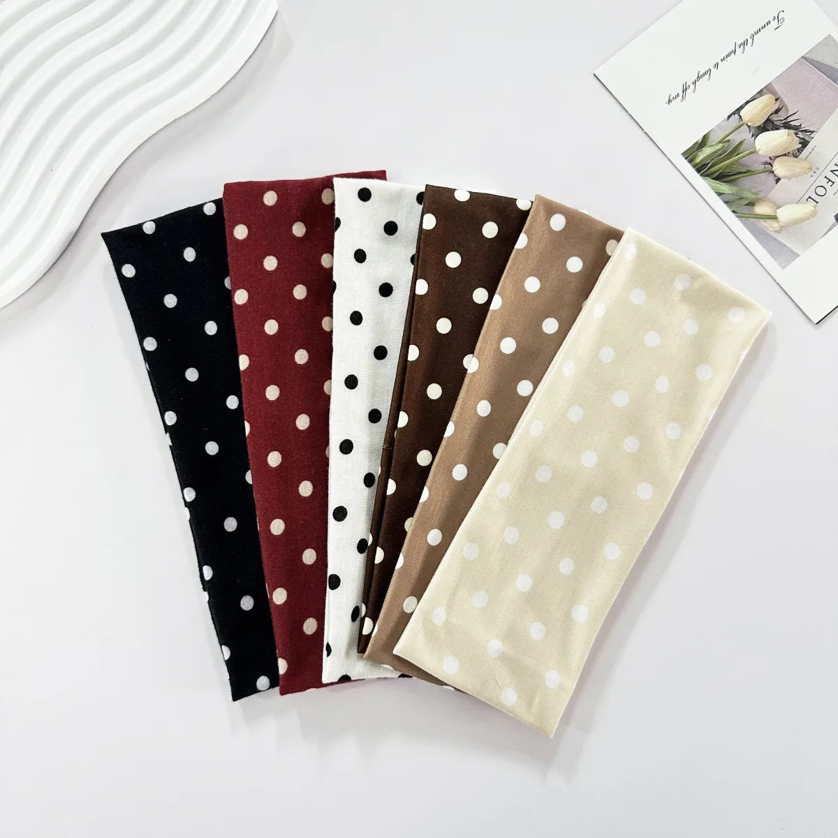 A collection of nine fabric hairbands in various colors and patterns, including polka dots and stripes.