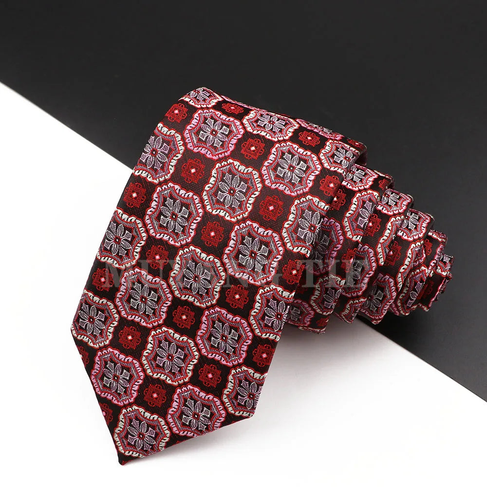 Eine Stapel luxuriöser Herrenkrawatten mit rotem und maroonem Blumen-Paisley-Muster.