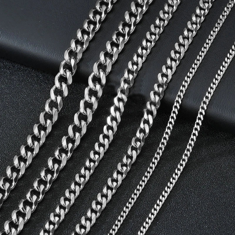 A close-up view of several silver-toned Cuban link chains arranged diagonally on a dark surface.