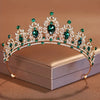 Diadema de tiara de cristal brillante con piedras verdes y detallado plateado intrincado.