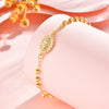 A close-up of an 18K gold plated rosary bracelet for women with a decorative pendant on a pink background.