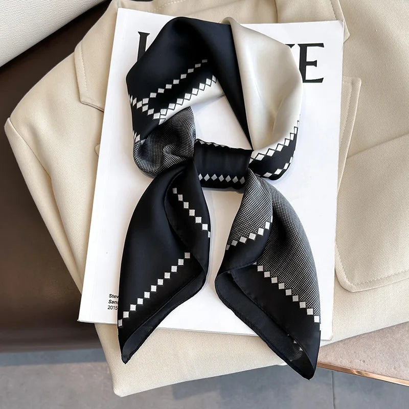 Black silk scarf with white geometric pattern tied in a bow, displayed on a white card.