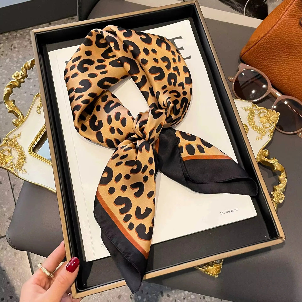 Luxuriöser Leopardenmuster-Seiderschal, gebunden in eine Schleife, präsentiert in einem schwarz-goldenen Rahmen.