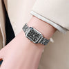 A close-up of an elegant gold plated quartz fashion watch with a black dial and silver-toned metal bracelet on a wrist.