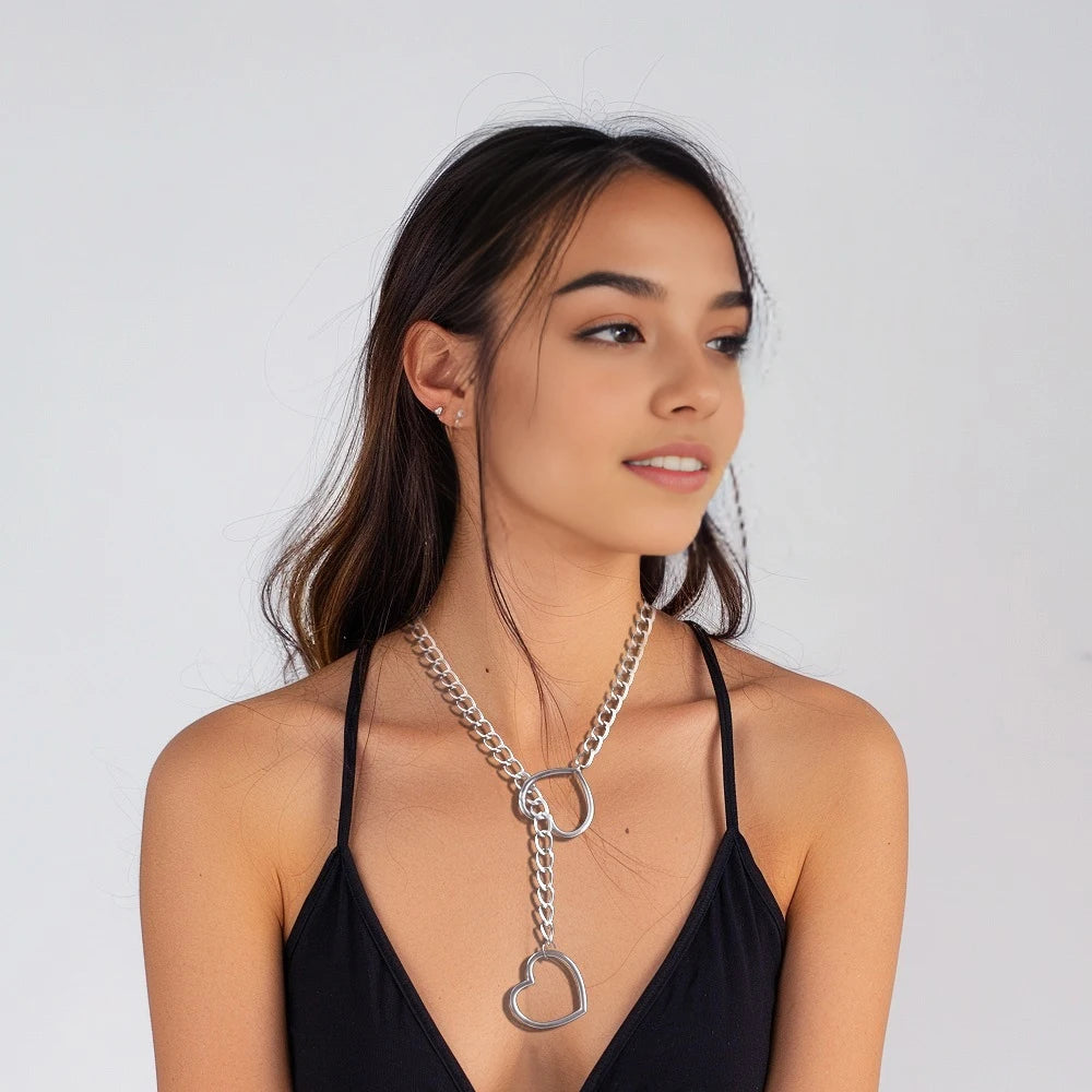 A young woman models a silver chunky heart slip chain necklace against a light gray background.