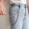A close-up of light wash denim jeans with a metal waist chain accessory being held by a hand.