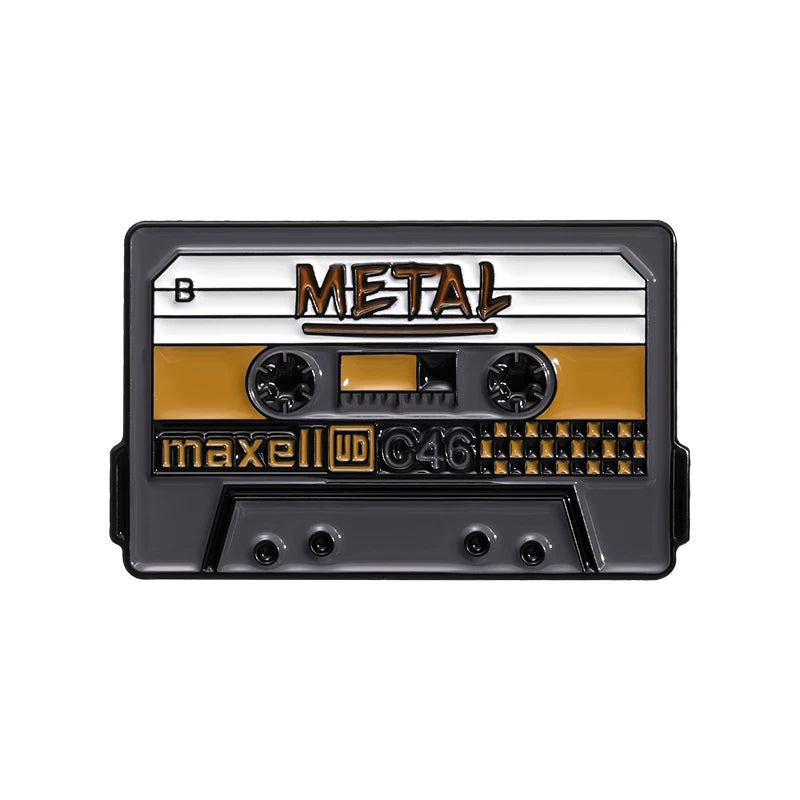 A black and gold enamel pin featuring the word METAL and a cassette tape design.