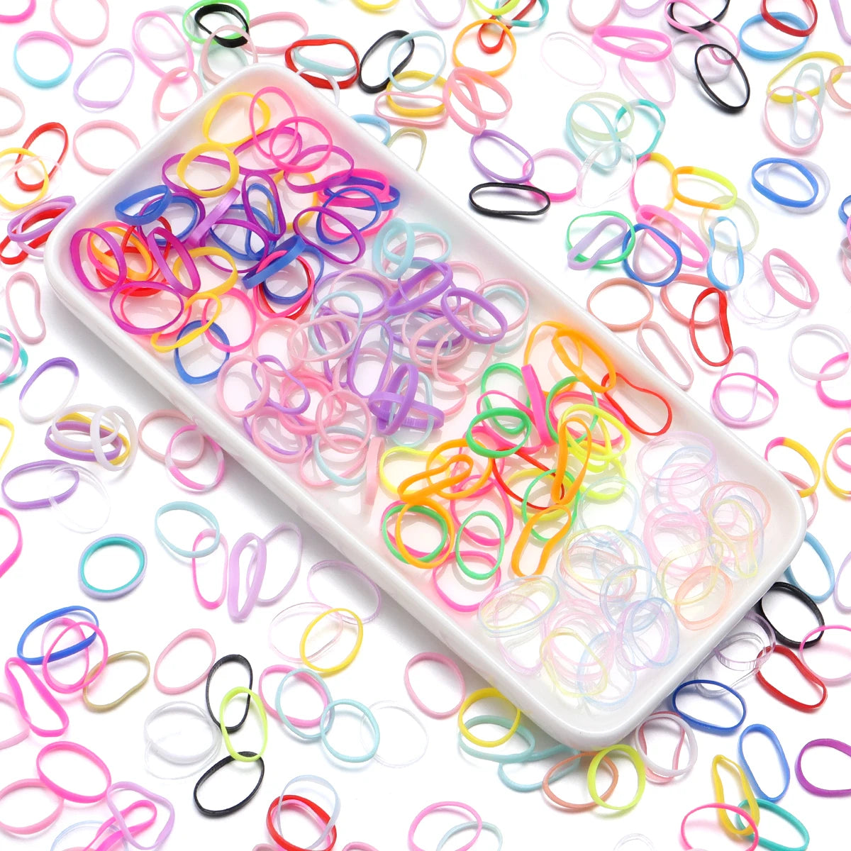 A white tray filled with colorful elastic hair ties in various bright colors like pink, blue, yellow, and green.