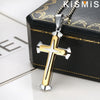 Colgante de cruz de acero inoxidable con detalles dorados, mostrado en una caja negra.