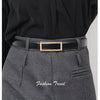 A close-up of a woman wearing a gray tailored skirt and a black belt with a gold buckle.