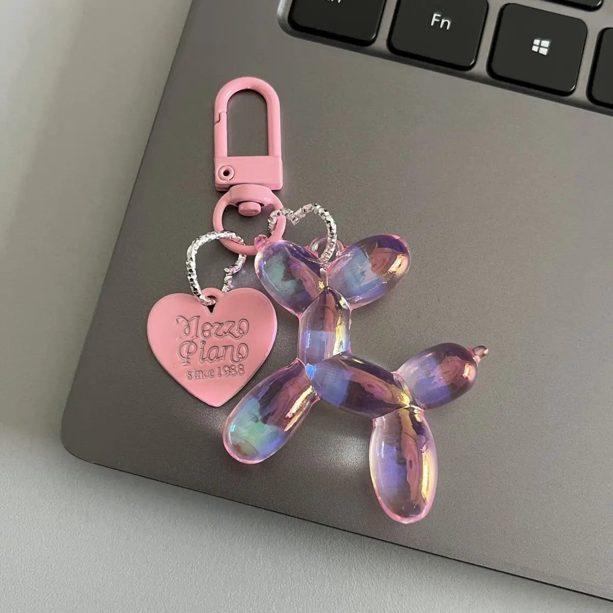 A pink resin animal dog keychain with a heart charm and silver chain attached to a pink keyring.