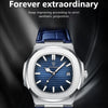 A close-up shot of a blue leather strap luxury men's watch with a silver case and blue dial against a dark background.
