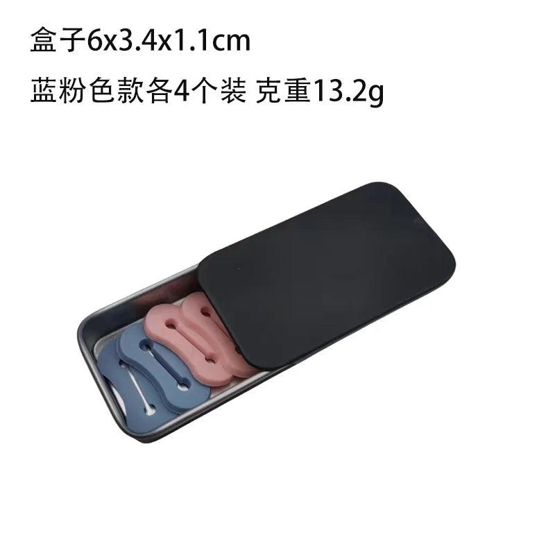 Una caja de plástico negro que contiene cuatro hebillas ajustables para extensiones de mangas de camisa rosa y azul.