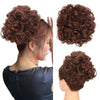 A close-up of a woman with reddish-brown hair styled in a voluminous curly chignon or messy bun.