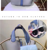 A light blue and pink portable eyewear storage pouch is displayed on a gold-toned stand.