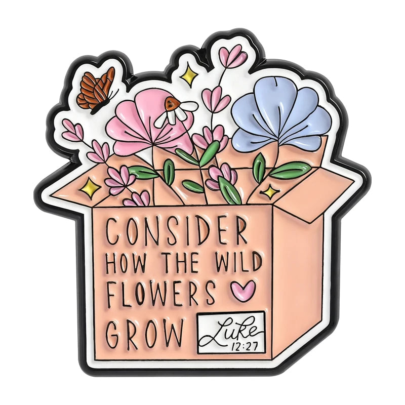 A pink and blue enamel flower brooch set featuring wildflowers and a message encouraging wild flowers to grow.