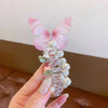 A pink fairy butterfly made of clear glass and pearl hair ropes held in a hand.