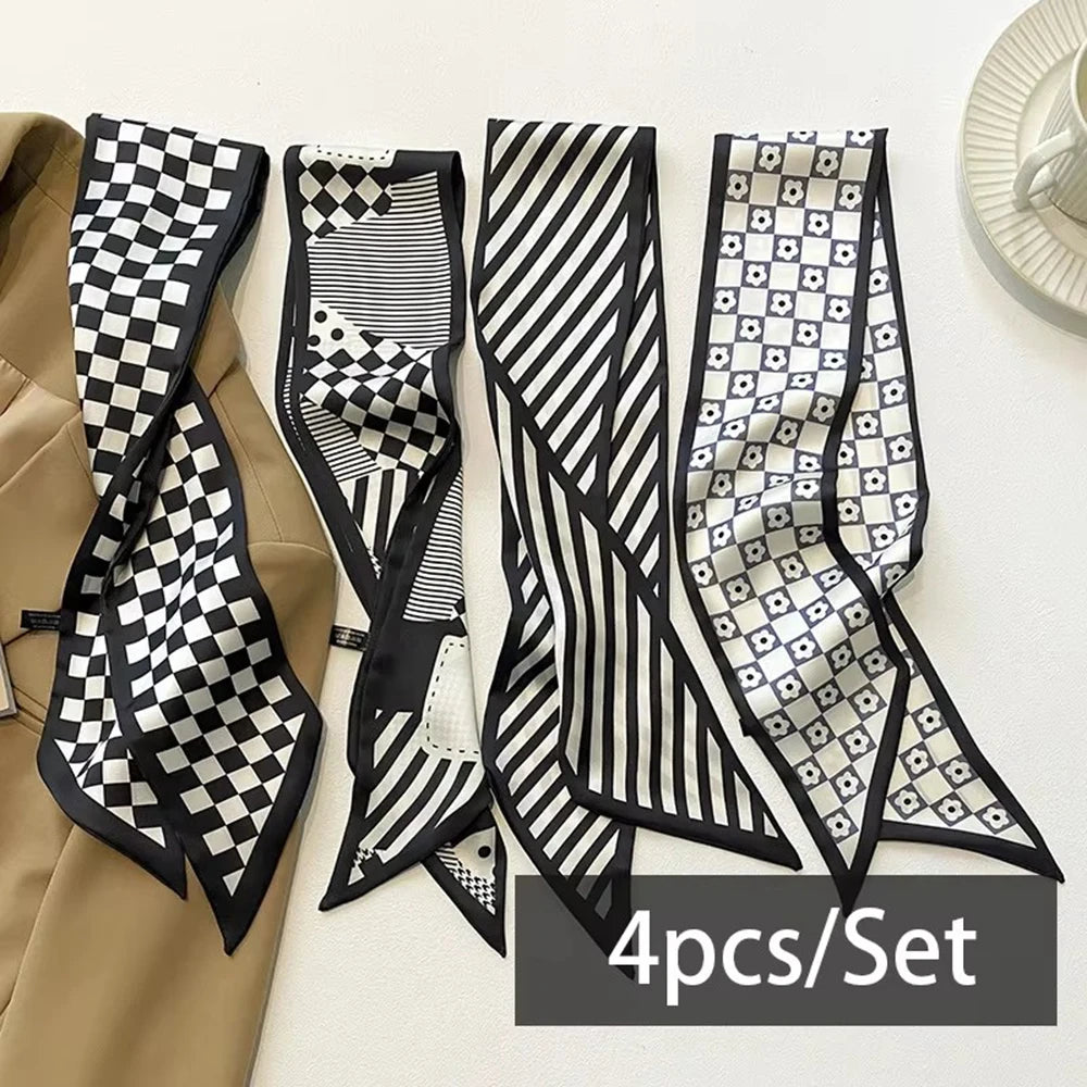 A set of four black and white patterned silk satin hair and bag accessories displayed on a white surface.