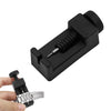 A black precision watch band link pin remover tool is shown next to a silver watch link.