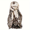 A beige leopard print satin silk scarf tied around a woman's hair