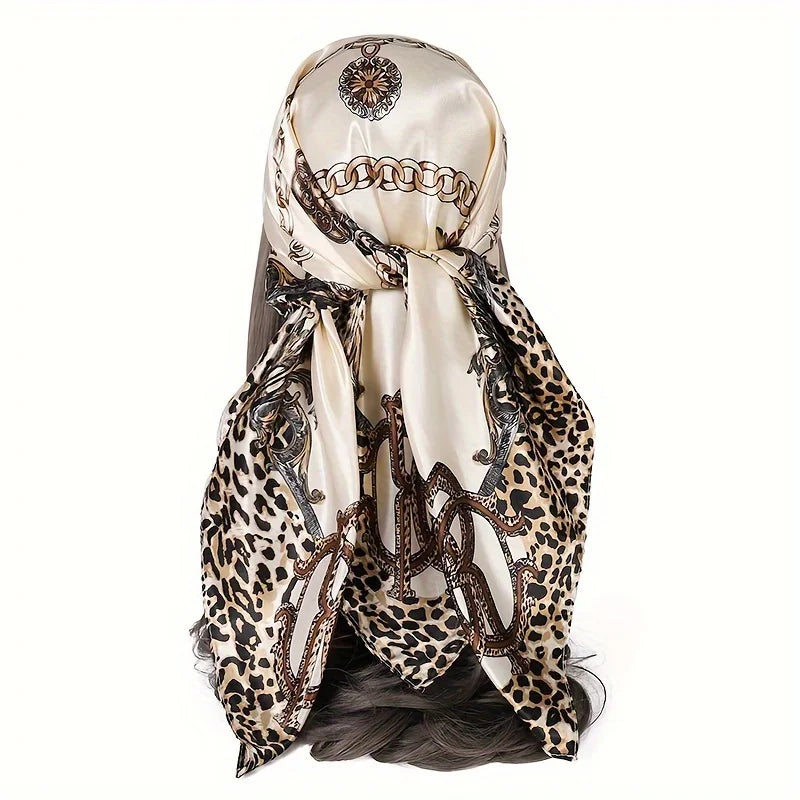 A beige leopard print satin silk scarf tied around a woman's hair