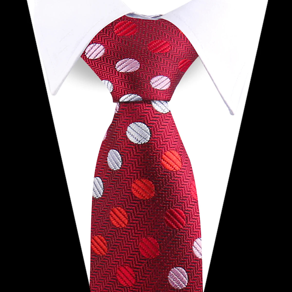 A red silk necktie with a paisley pattern featuring silver and pink polka dots, shown against a white shirt.