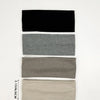 A set of four knitted hair bands in black, gray, taupe, and beige stacked vertically.
