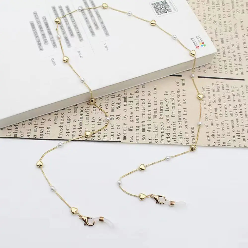 A delicate chain lanyard made of pearls is displayed against a background featuring printed text.