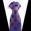 A close-up of an elegant men's floral paisley silk necktie with purple, pink, and blue patterns against a white shirt.