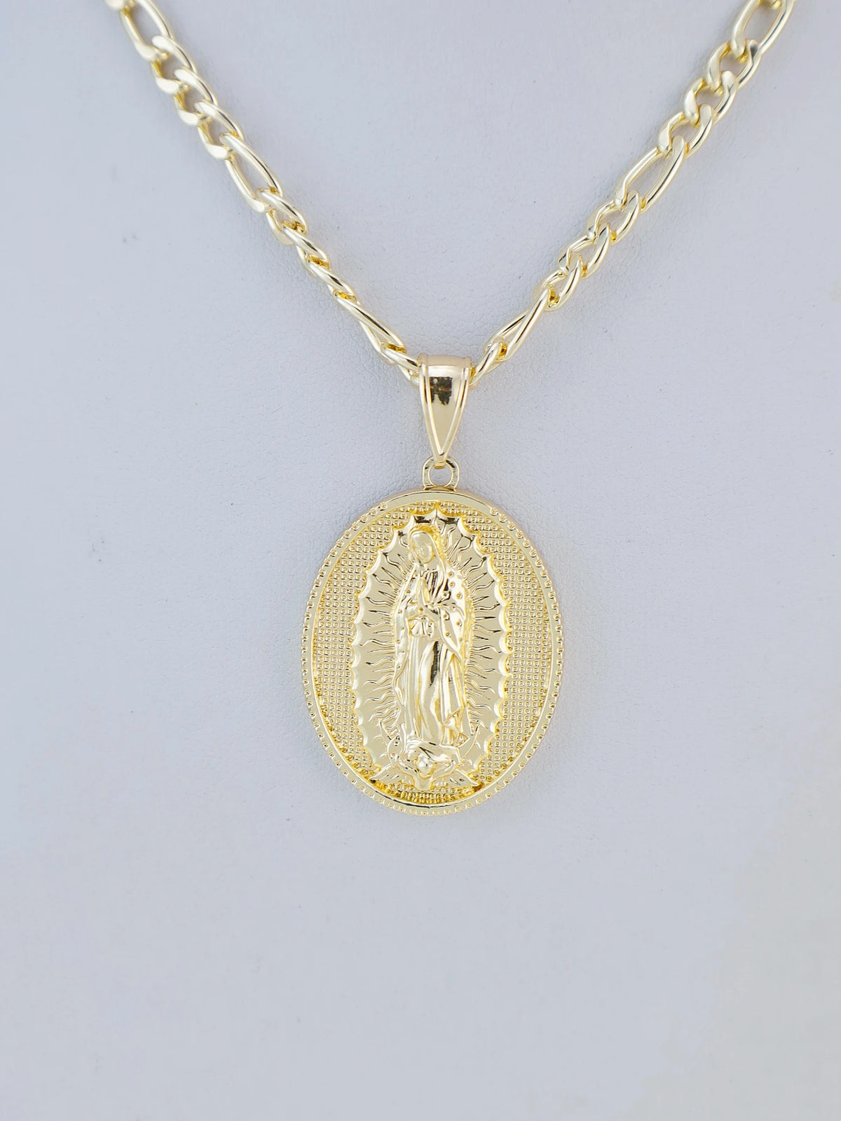 A gold plated pendant necklace featuring a detailed depiction of the Virgin Mary Christ.