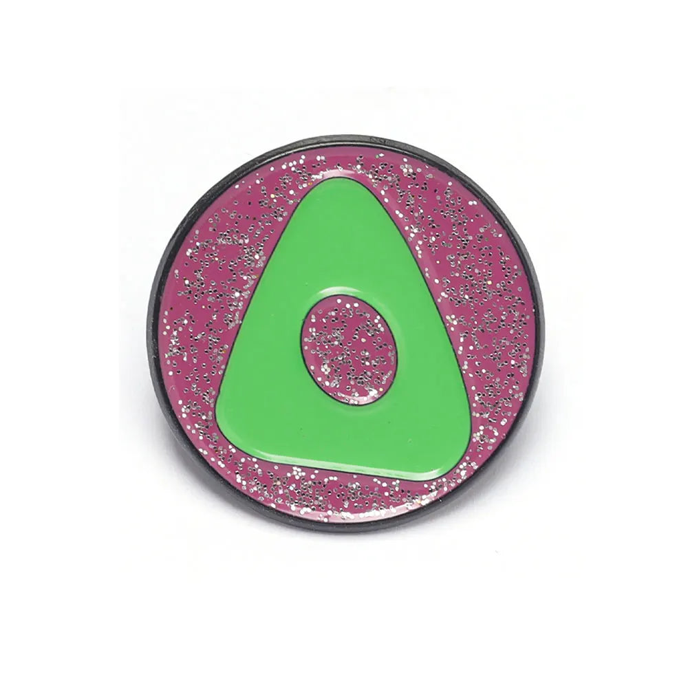 Une épingle émail ronde avec un triangle vert vif sur un fond magenta scintillant.