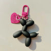 A black jelly cartoon dog keychain with a pink heart tag and silver keyring.