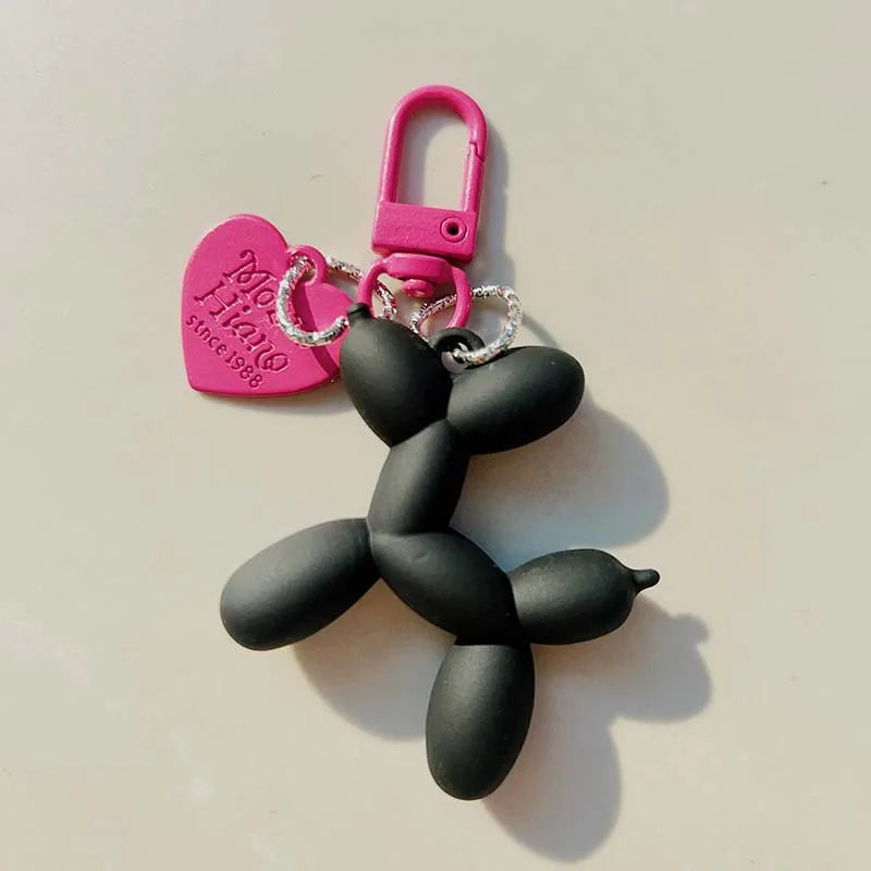 A black jelly cartoon dog keychain with a pink heart tag and silver keyring.