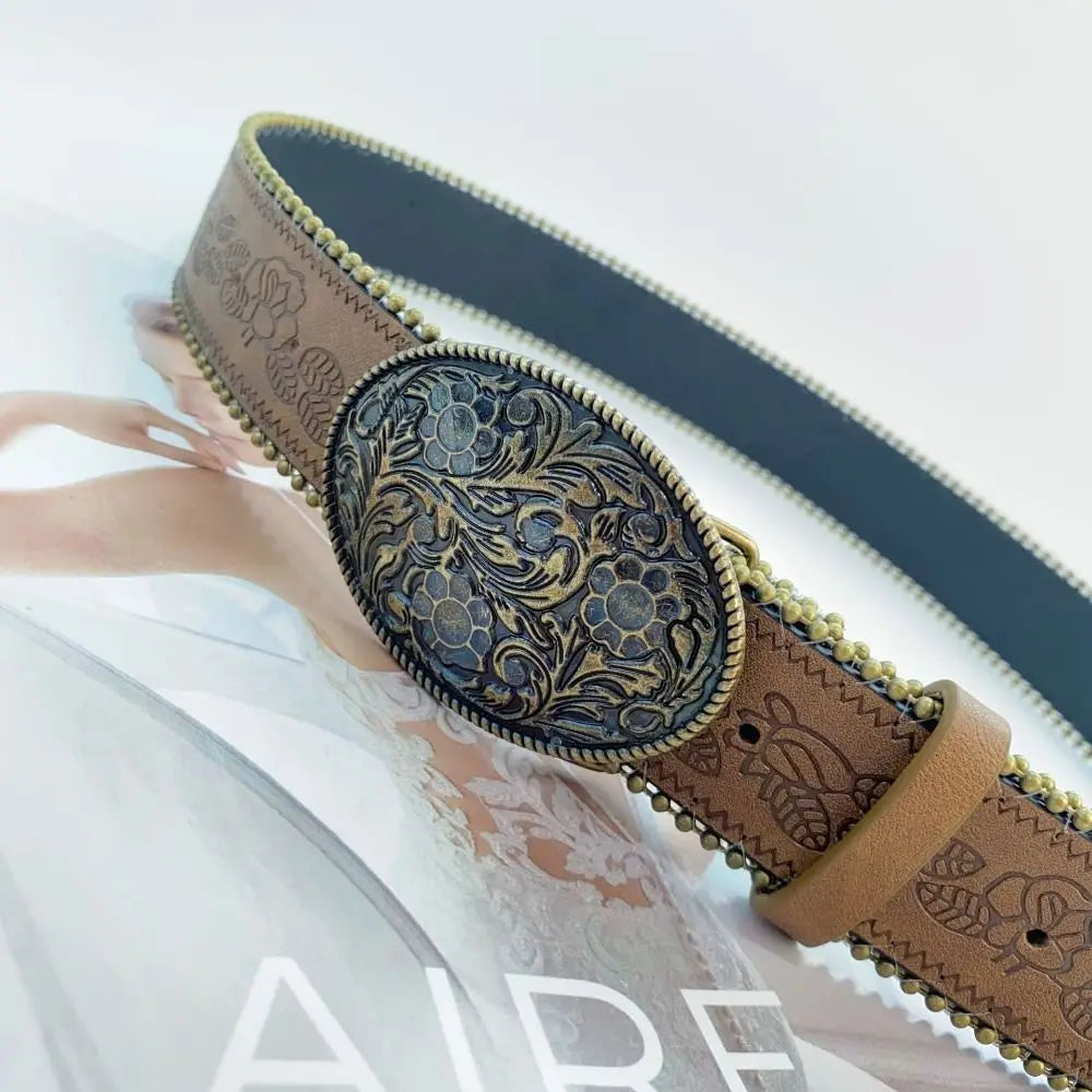 A close-up of a vintage PU leather boho western belt with a dark floral pattern and gold accents.